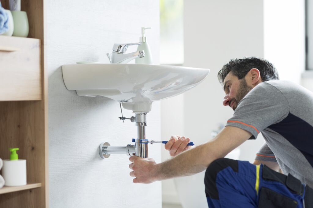 plumber fixing slow drains in your home with professional drain cleaning equipment
