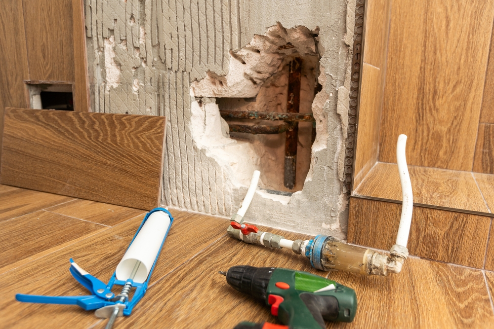 Contractor inspecting plumbing mistakes during renovations in a residential home