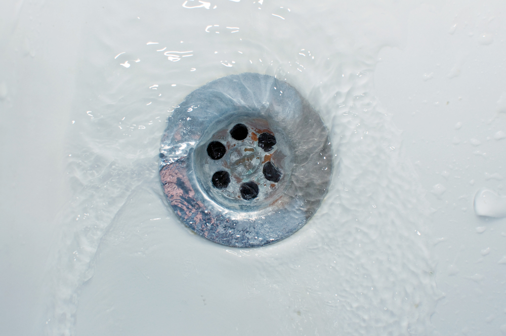 Professional plumber inspecting recurring drain problems in a residential plumbing system