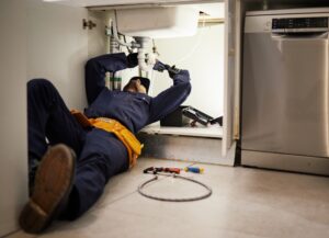 Professional plumber inspecting small plumbing issues in a home to prevent long-term property damage