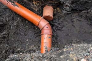 Professional plumber inspecting an underground sewer line after landscaping changes in a residential yard